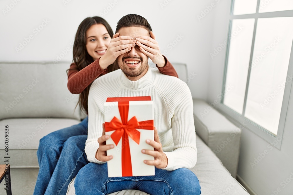 Young hispanic couple smiling happy surprising with birthday gift at home. Young hispanic couple smiling happy surprising with birthday gift at home.