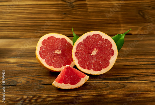 cut grapefruit on a wooden background with green leaves