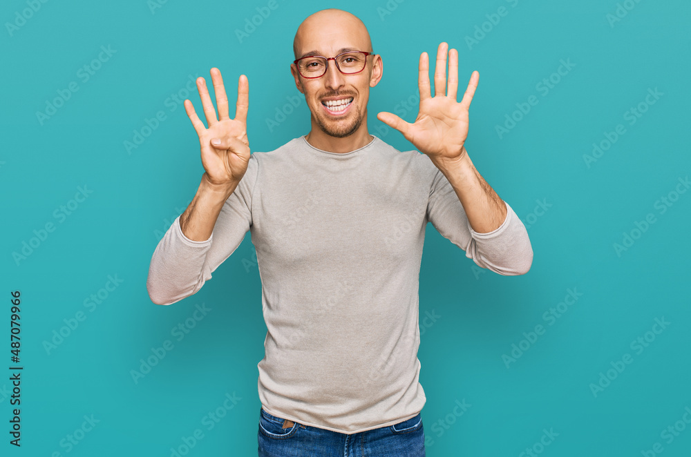Bald man with beard wearing casual clothes and glasses showing and pointing up with fingers number nine while smiling confident and happy.