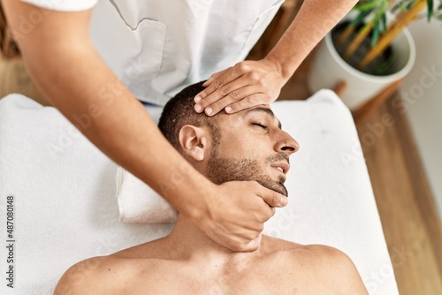 Two hispanic men therapist and patient having facial massage at beauty center