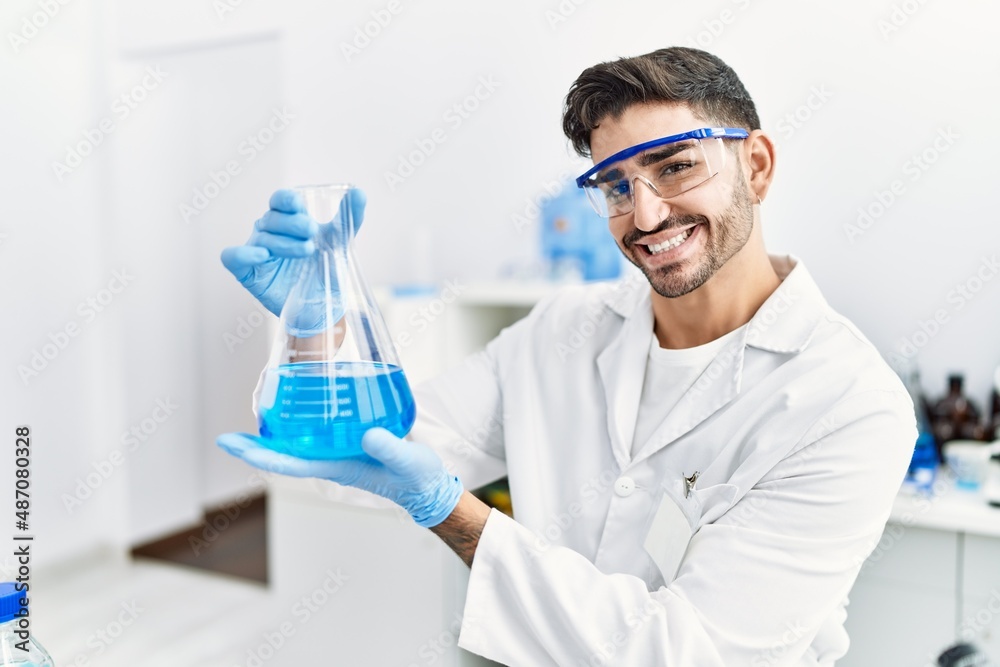 Handsome hispanic man working as scientific holding erlenmeyer flask at laboratory Handsome hispanic man working as scientific holding erlenmeyer flask at laboratory