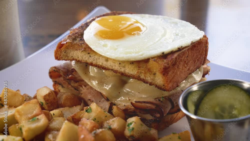 A brunch sandwich topped with a sunny side up egg and paired with hash browns, slider close up 4K A brunch sandwich topped with a sunny side up egg and paired with hash browns, slider close up 4K