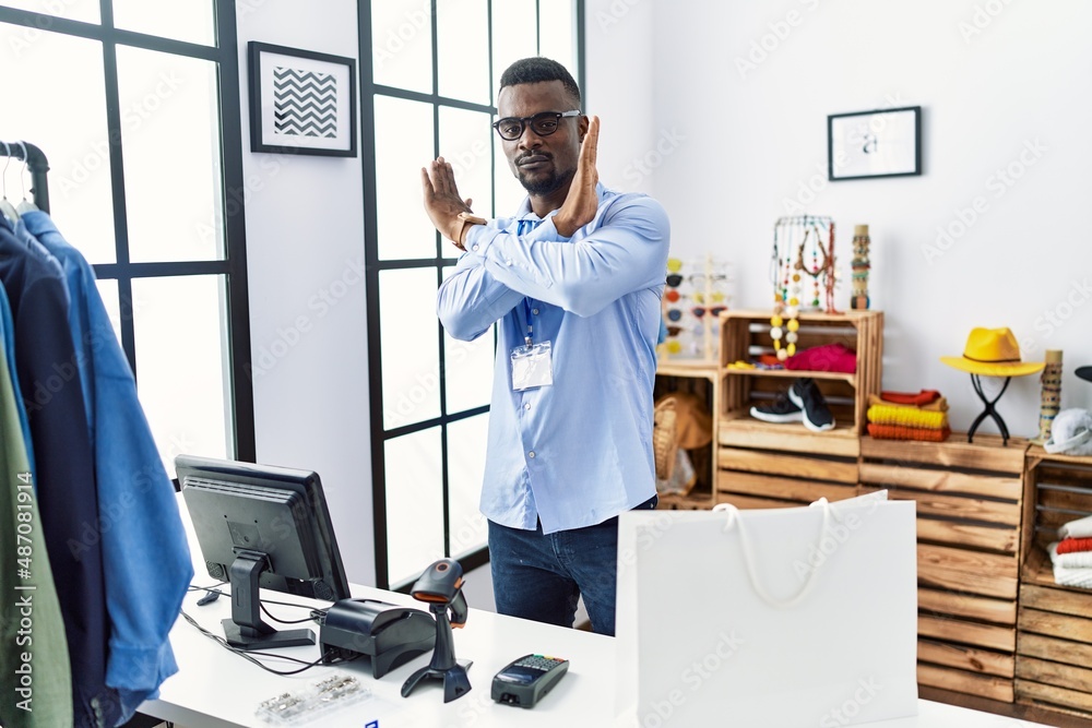 Young african man working as manager at retail boutique rejection expression crossing arms doing negative sign, angry face Young african man working as manager at retail boutique rejection expression crossing arms doing negative sign, angry face