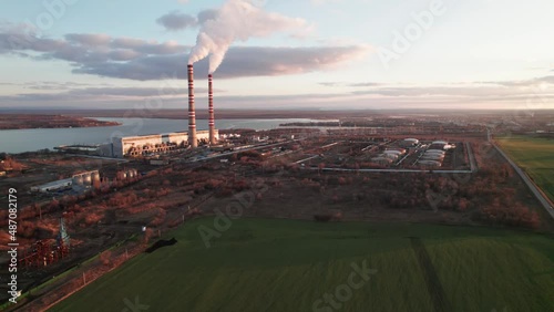 Flight with a view of a thermal power plant with smoking pipes on the background of a reservoir in Russia