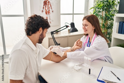 Man and woman wearing doctor uniform having blood analysis at clinic