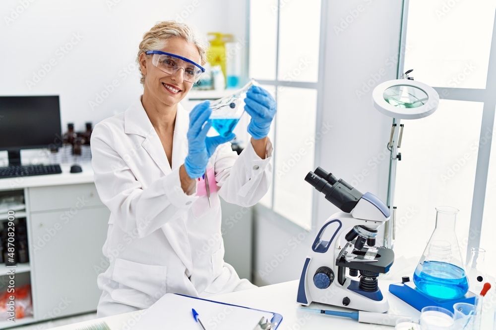 Middle age blonde woman wearing scientist uniform holding test tube at laboratory Middle age blonde woman wearing scientist uniform holding test tube at laboratory