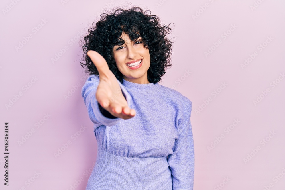 Young middle east woman wearing casual clothes smiling friendly offering handshake as greeting and welcoming. successful business. Young middle east woman wearing casual clothes smiling friendly offering handshake as greeting and welcoming. successful business.