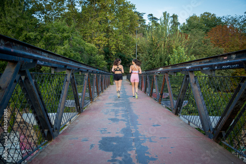 young female couple running in sportswear on a bridge