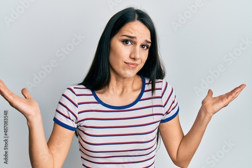 Young hispanic woman wearing casual clothes clueless and confused with open arms  no idea and doubtful face.