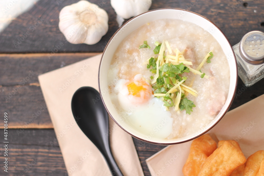 Joke or Congee in a Thai style cup Served on a black wooden table. It's an Asian breakfast. on top view