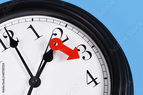 Summer time change for daylight saving in Europe concept. Red arrow symbolizing clock turned forward by one hour photo