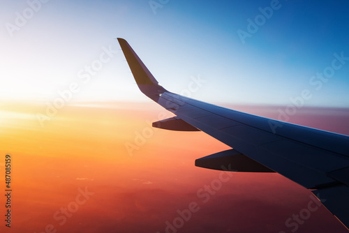 Obraz na płótnie View from the window of the aircraft on the wing over the colorful sunset and illuminated vivid clouds w salonie