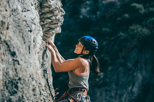 Woman climbing a rock with extreme effort in a vertical rock wall photo