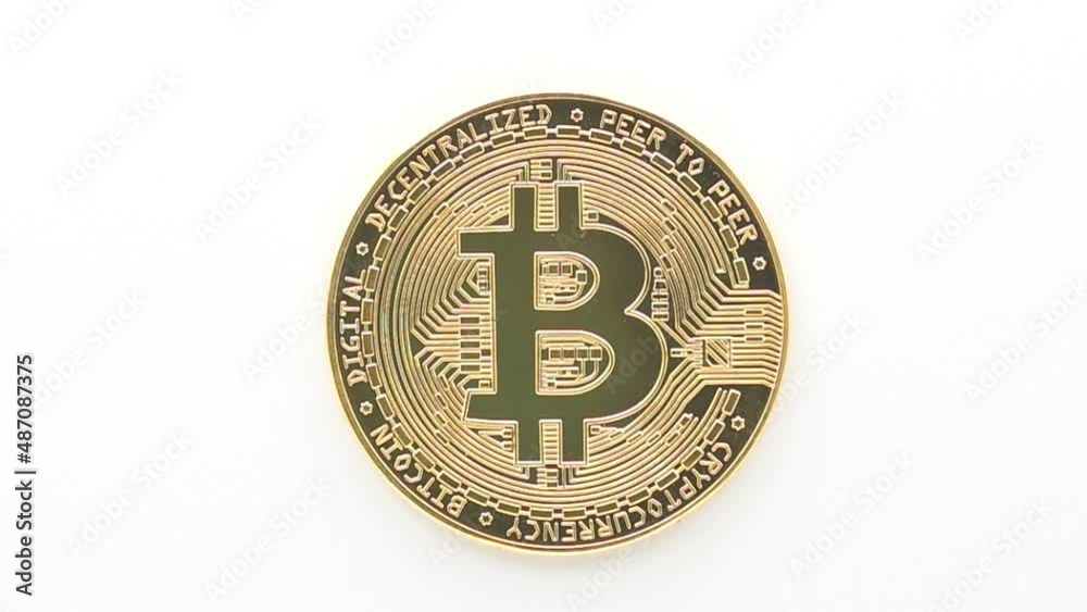 Real golden metal bitcoin isolated on white background with panning effect and with light turning on and off.