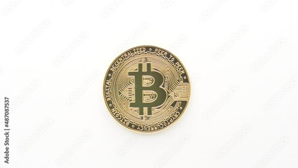 Real gold metal bitcoin isolated on white background with light that turns on and off and with zoom out effect. Real gold metal bitcoin isolated on white background with light that turns on and off and with zoom out effect.