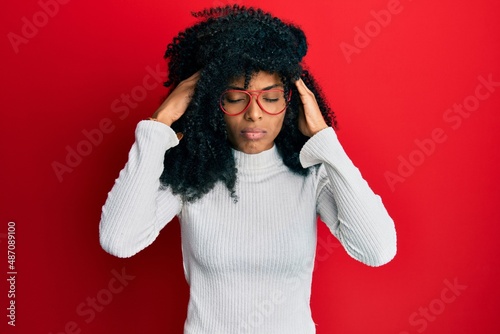 African american woman with afro hair wearing casual sweater and glasses with hand on head  headache because stress. suffering migraine.