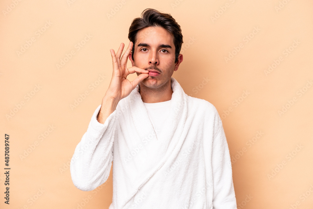 Young caucasian man wearing a bathrobe isolated on beige background with fingers on lips keeping a secret. Young caucasian man wearing a bathrobe isolated on beige background with fingers on lips keeping a secret.