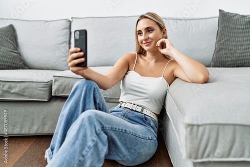 Young blonde woman smiling confident making selfie by the smartphone at home