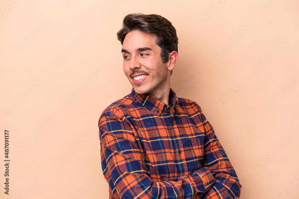 Young caucasian man isolated on beige background laughing and having fun. Young caucasian man isolated on beige background laughing and having fun.