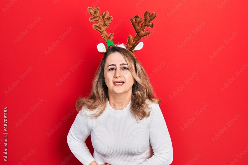 Middle age caucasian woman wearing cute christmas reindeer horns with hand on stomach because indigestion, painful illness feeling unwell. ache concept.