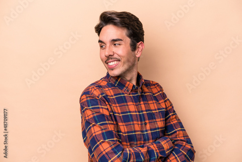 Young caucasian man isolated on beige background laughing and having fun.