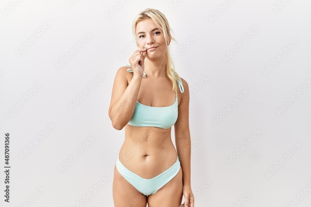 Young caucasian woman wearing bikini over isolated background mouth and lips shut as zip with fingers. secret and silent, taboo talking Young caucasian woman wearing bikini over isolated background mouth and lips shut as zip with fingers. secret and silent, taboo talking