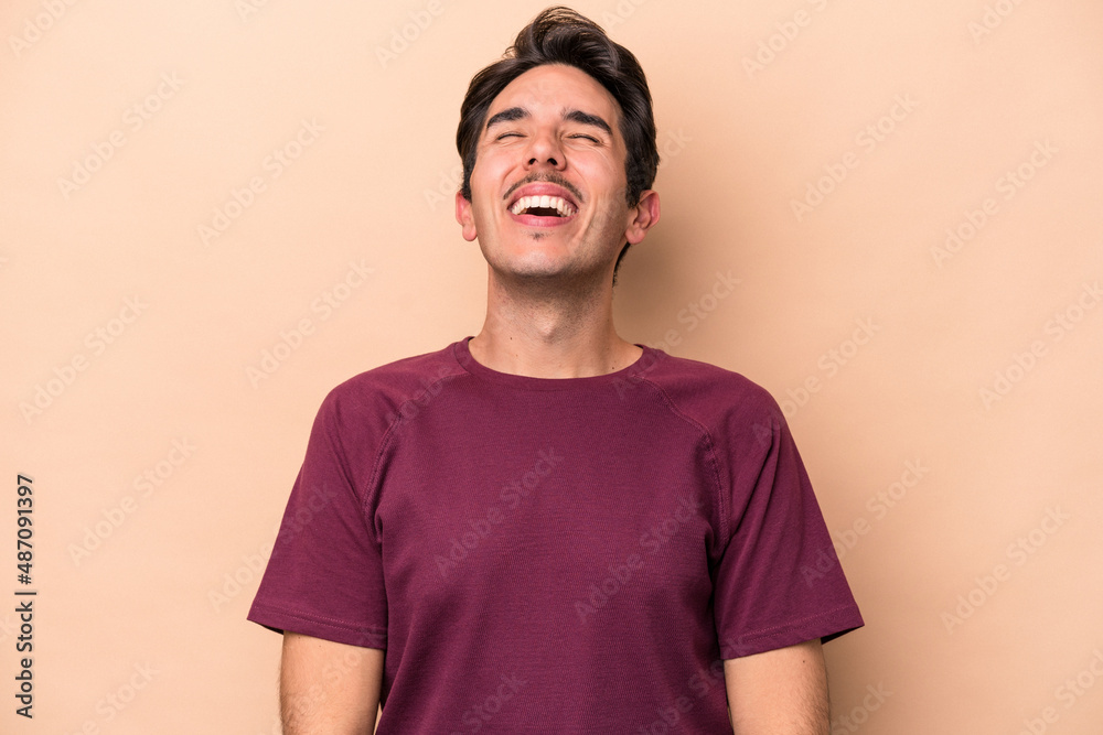Young caucasian man isolated on beige background relaxed and happy laughing, neck stretched showing teeth. Young caucasian man isolated on beige background relaxed and happy laughing, neck stretched showing teeth.