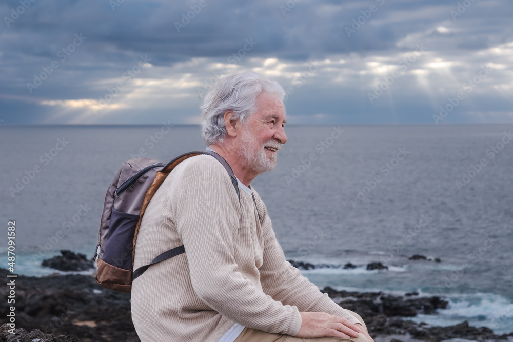 Fototapeta premium Adult old senior bearded man resting during excursion at sea looking at horizon over water. Caucasian elderly white-haired male enjoying free time, vacation and nature in seascape. Copy space