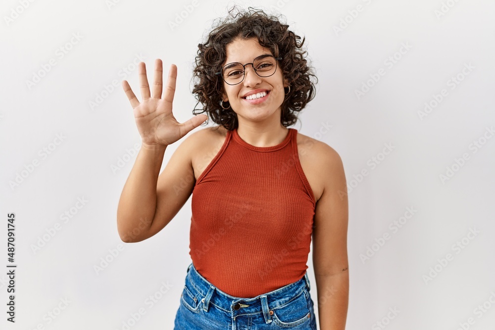 Young hispanic woman wearing glasses standing over isolated background showing and pointing up with fingers number five while smiling confident and happy. Young hispanic woman wearing glasses standing over isolated background showing and pointing up with fingers number five while smiling confident and happy.
