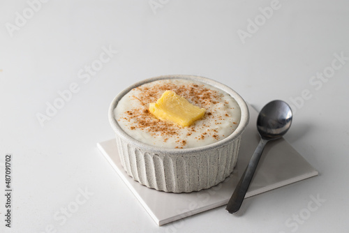 Close upf of Risengrod, rice pudding or porridge with butter and cinnamon on kitchen table .