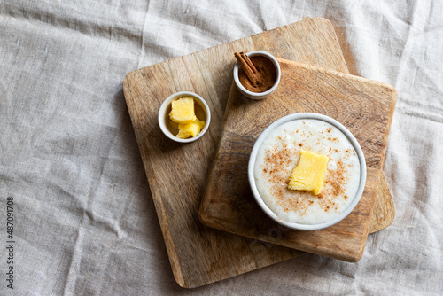 Top view of Scandinavian rice porridge or Risengrod with butter and cinnamon on linen table setting.