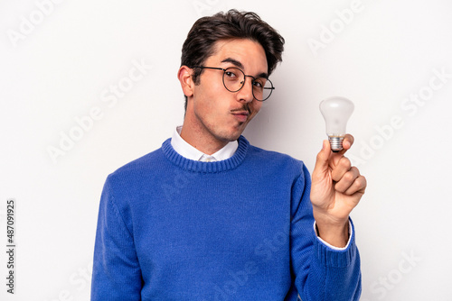 Young caucasian man holding a lightbulb isolated on white background