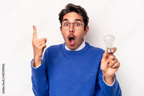 Young caucasian man holding a lightbulb isolated on white background