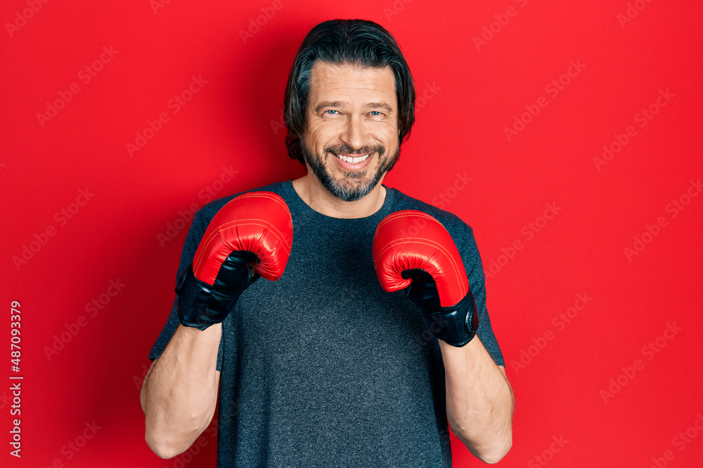 Middle age caucasian man using boxing gloves smiling with a happy and cool smile on face. showing teeth.
