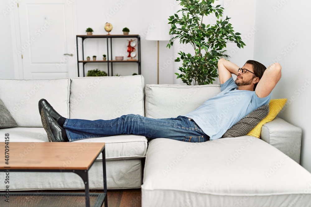 Middle age caucasian man relaxed with hands on head lying on sofa at home Middle age caucasian man relaxed with hands on head lying on sofa at home
