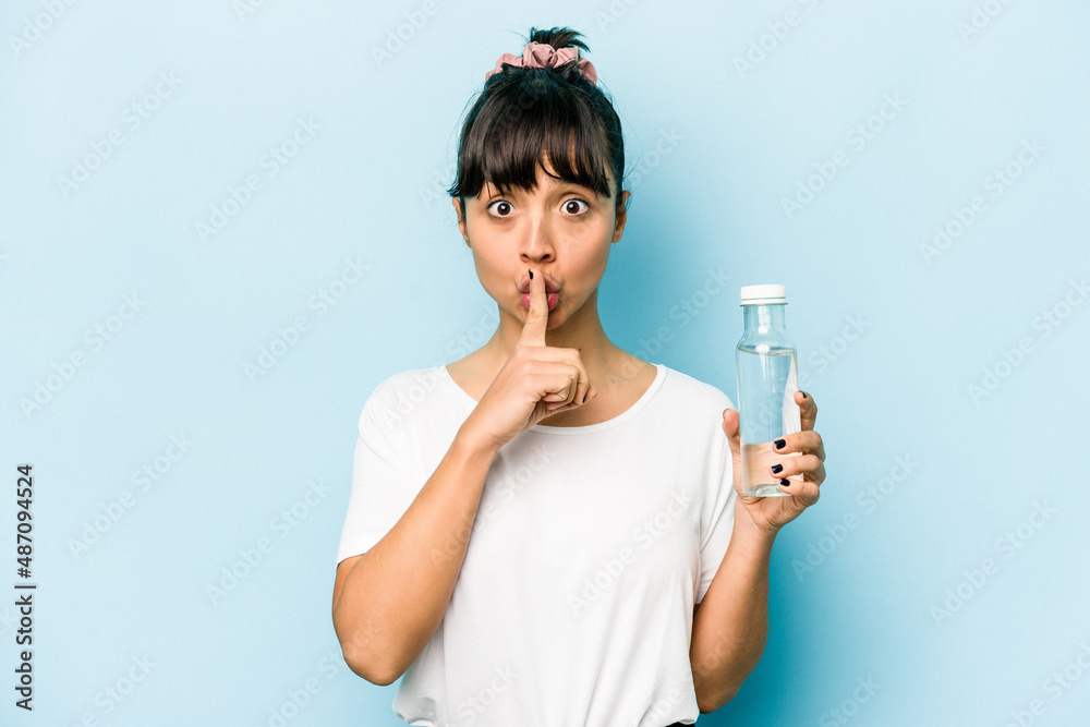 Young hispanic woman holding a bottle of water isolated on blue background keeping a secret or asking for silence. Young hispanic woman holding a bottle of water isolated on blue background keeping a secret or asking for silence.