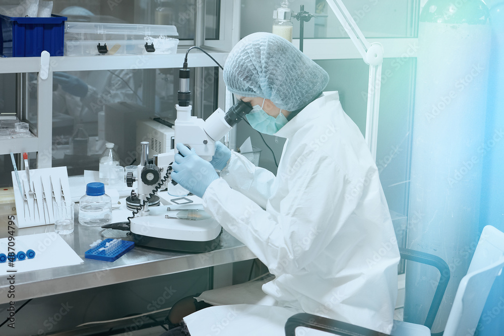 Medic or scientist looking through a microscope in a scientific medical laboratory. Biochemical research and medicine Medic or scientist looking through a microscope in a scientific medical laboratory. Biochemical research and medicine