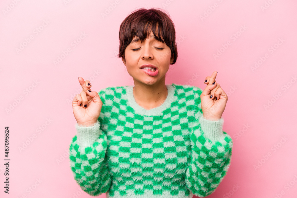Young hispanic woman isolated on pink background crossing fingers for having luck Young hispanic woman isolated on pink background crossing fingers for having luck
