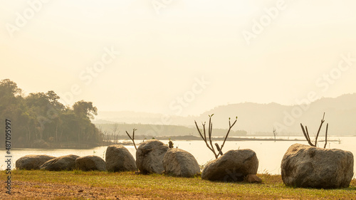 Sunlight shining in the mist in the morning , The stones are arranged along the reservoir.