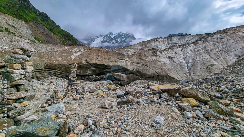 Stacked stones in front of the Shkhara Glacier in the Greater Caucasus Mountain Range in Georgia, Svaneti Region, Ushguli. Wanderlust, Stone cairns. Freedom. Glacier melting. Patara enguri river. Stacked stones in front of the Shkhara Glacier in the Greater Caucasus Mountain Range in Georgia, Svaneti Region, Ushguli. Wanderlust, Stone cairns. Freedom. Glacier melting. Patara enguri river.