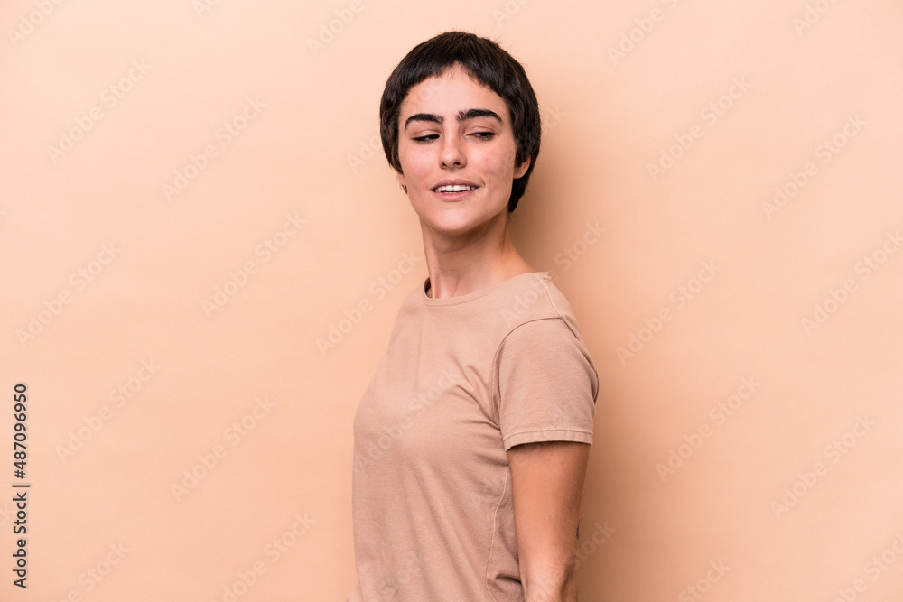 Young caucasian woman isolated on beige background looks aside smiling, cheerful and pleasant. Young caucasian woman isolated on beige background looks aside smiling, cheerful and pleasant.