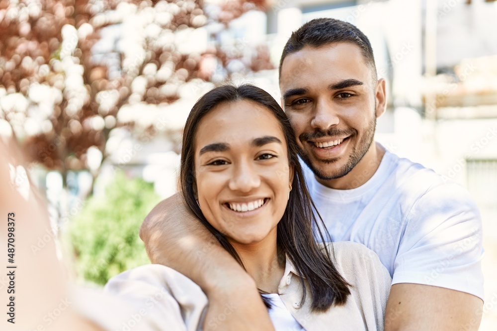 Young latin couple smiling happy and hugging making selfie by the camera at the city. Young latin couple smiling happy and hugging making selfie by the camera at the city.