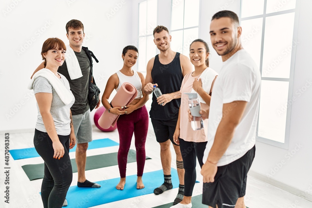 Fototapeta premium Group of young sporty people smiling happy and looking to the camera at sport center.
