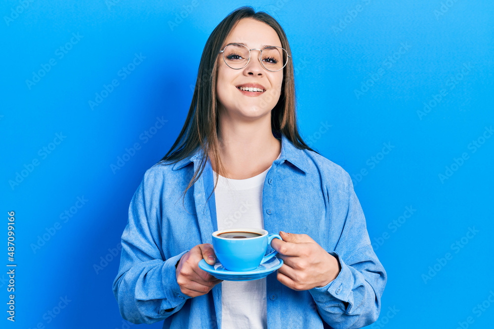 Young hispanic girl drinking a cup of coffee smiling and laughing hard out loud because funny crazy joke. Young hispanic girl drinking a cup of coffee smiling and laughing hard out loud because funny crazy joke.