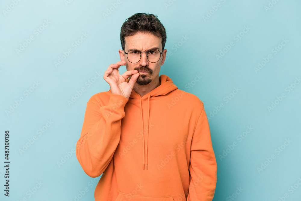 Young caucasian man isolated on blue background with fingers on lips keeping a secret. Young caucasian man isolated on blue background with fingers on lips keeping a secret.