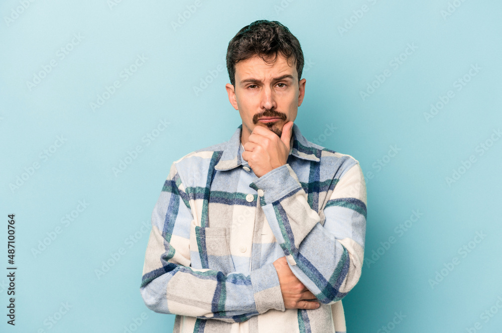 Young caucasian man isolated on blue background thinking and looking up, being reflective, contemplating, having a fantasy. Young caucasian man isolated on blue background thinking and looking up, being reflective, contemplating, having a fantasy.