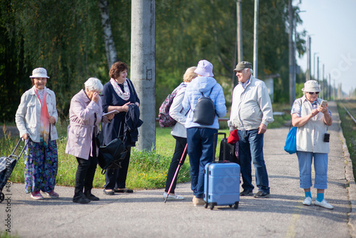 A group of happy senior friends with suitcases waiting for a train on the platform