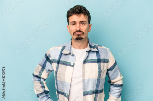 Young caucasian man isolated on blue background sad, serious face, feeling miserable and displeased.