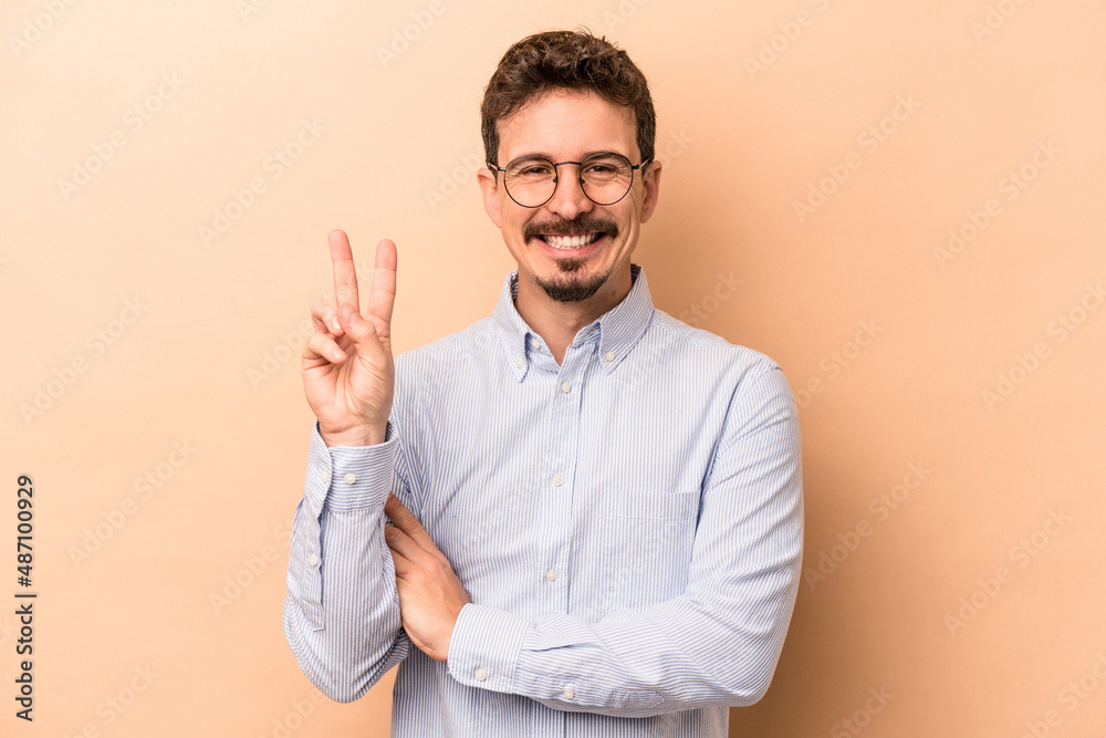 Young caucasian man isolated on beige background showing number two with fingers. Young caucasian man isolated on beige background showing number two with fingers.