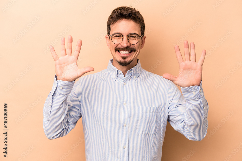 Young caucasian man isolated on beige background showing number ten with hands. Young caucasian man isolated on beige background showing number ten with hands.
